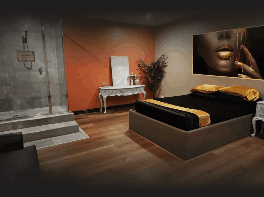 Luxurious private massage room with gold-accented bed and warm ambient lighting at Luxxx Erotic Massage in Melbourne