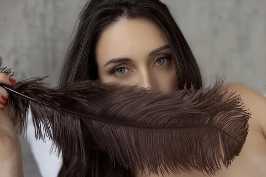Tantra massage Sydney, blue eyes behind a brown feather for sensual teasing