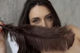 Tantra massage Sydney, blue eyes behind a brown feather for sensual teasing
