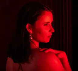 Sunshine Coast erotic massage, brunette looking over her bare shoulder in red light Sunshine Coast erotic massage, brunette looking over her bare shoulder in red light