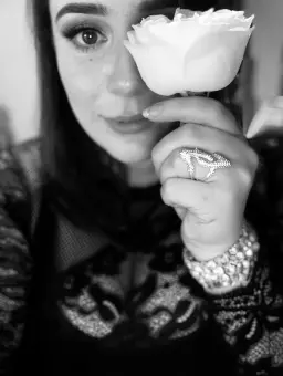 Adult massage Windsor masseuse holding a white rose to her face in black and white Adult massage Windsor masseuse holding a white rose to her face in black and white