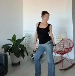 Erotic massage Perth, brunette masseuse in a black tank top and blue jeans by a red chair Erotic massage Perth, brunette masseuse in a black tank top and blue jeans by a red chair