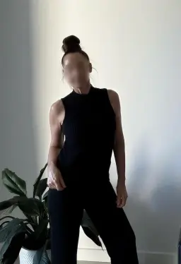Perth erotic massage, brunette masseuse in a black high neck top, backlit against a white wall Perth erotic massage, brunette masseuse in a black high neck top, backlit against a white wall
